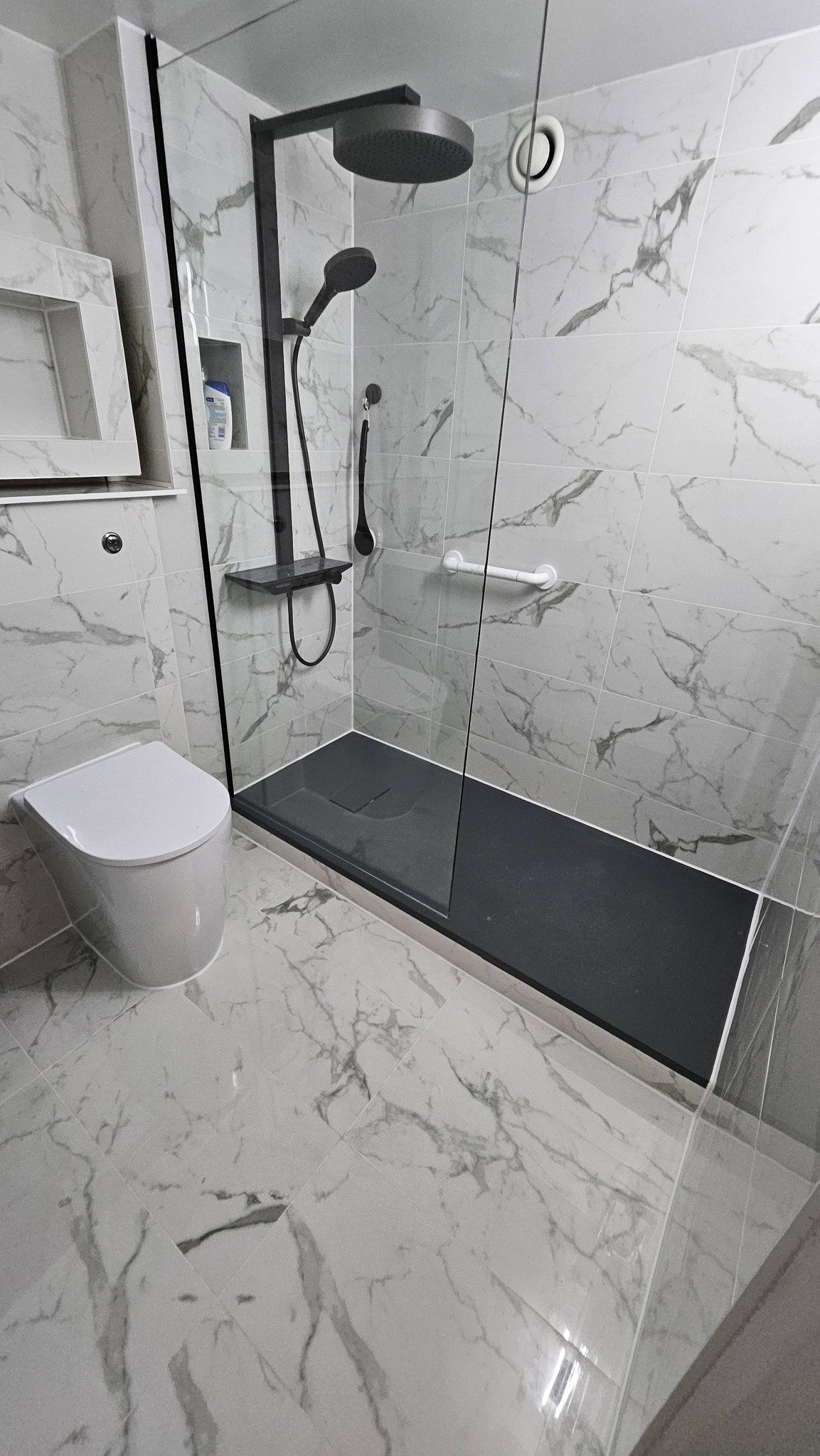 After: Marble walk-in shower with black fixtures